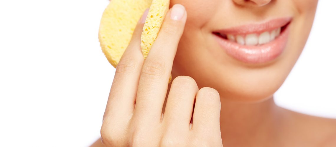 Fresh woman cleaning her face with sponge